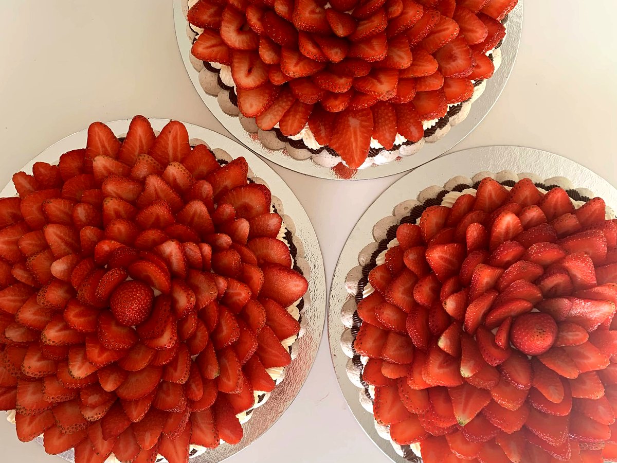 Three Cakish strawberry pavlovas in different sizes, viewed from above, showing the beautiful strawberry floral arrangement.