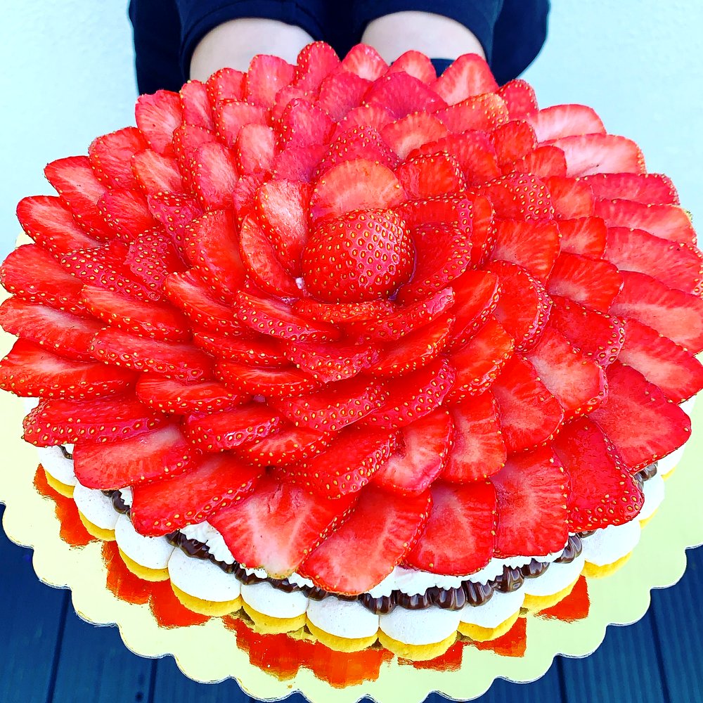 Close-up detail of a Cakish pavlova showing the intricate strawberry floral pattern and layers of cream and meringue.